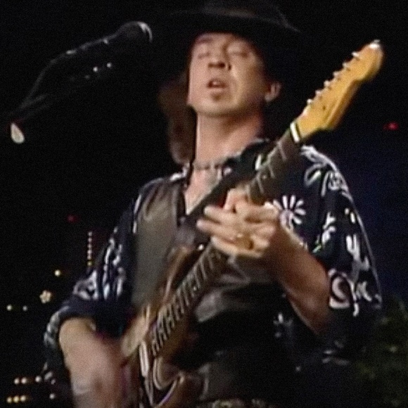 Stevie Ray Vaughan playing guitar at a concert.